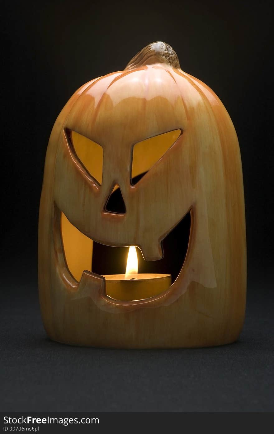 Ceramic pumpkin with tea candle burning on black background. Ceramic pumpkin with tea candle burning on black background.