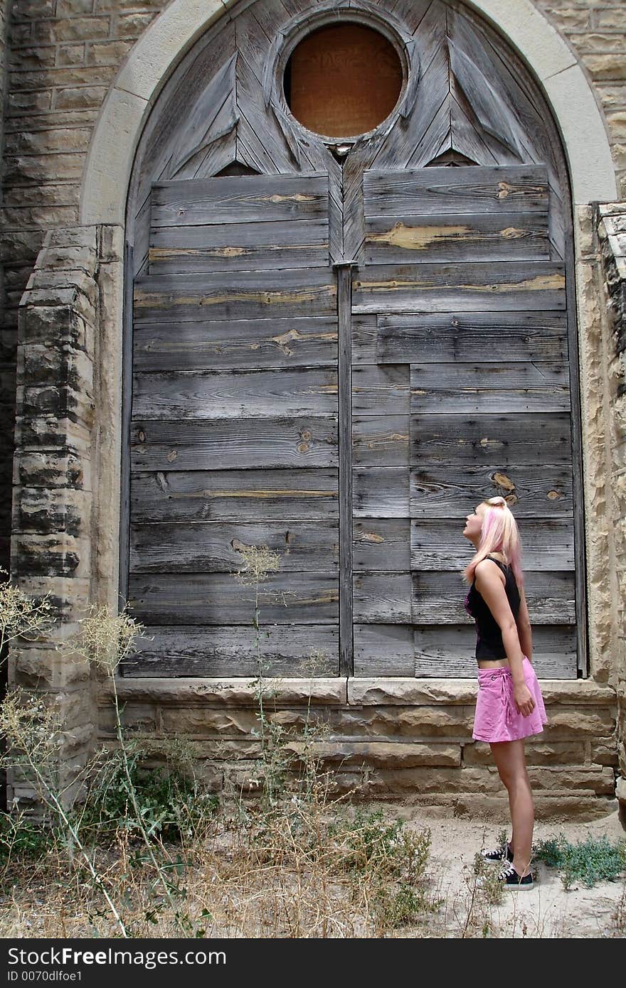 Punk girl standing outside looking up at an old church. Punk girl standing outside looking up at an old church.