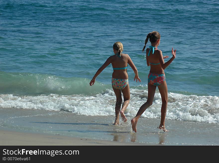 Two teenage girls are running to the water. Two teenage girls are running to the water