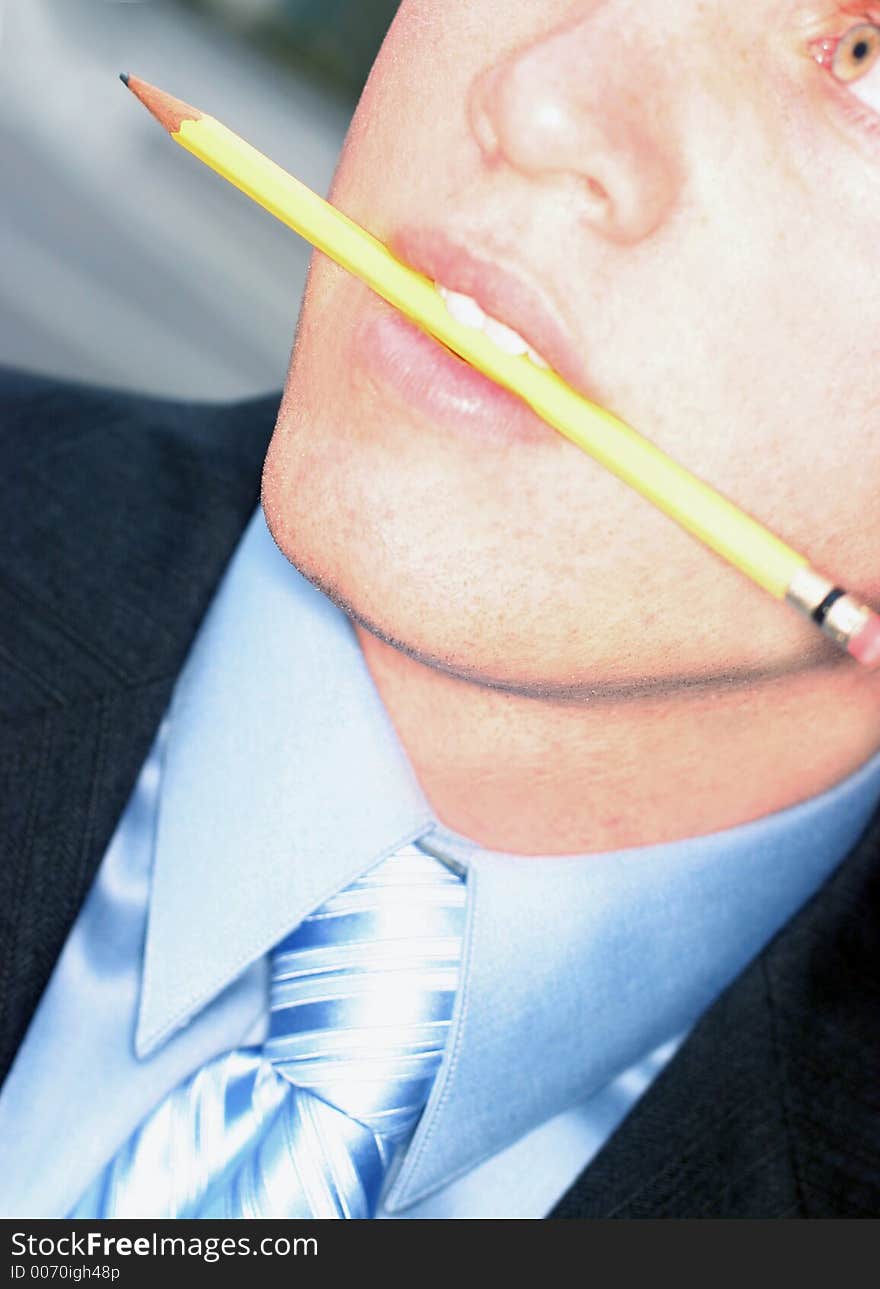 Business man biting pencil