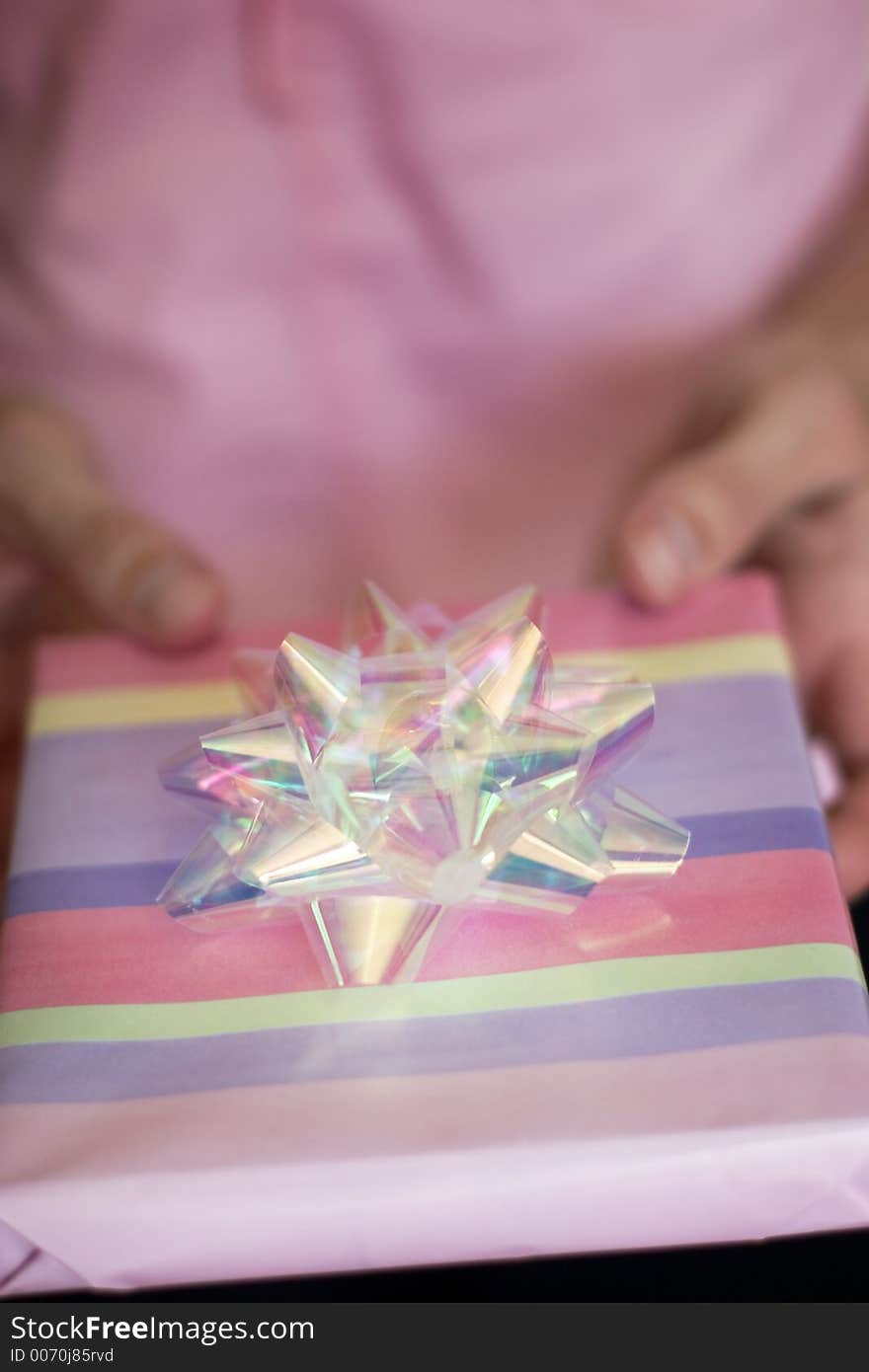 Woman dressed in pink holds out a gift