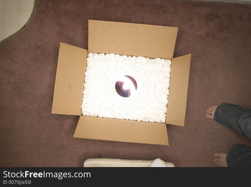 Reflective object in the middle of an open box on pink carpet. Reflective object in the middle of an open box on pink carpet