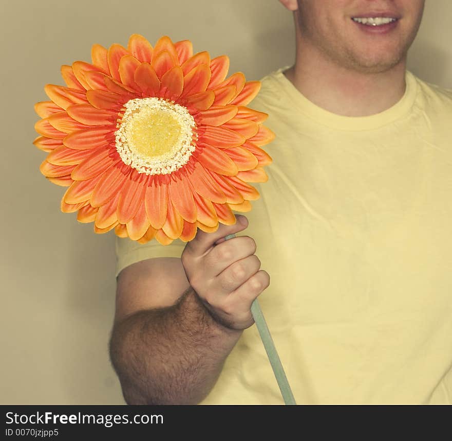 Man in yellow shirt holds orange, yellow flower. Man in yellow shirt holds orange, yellow flower