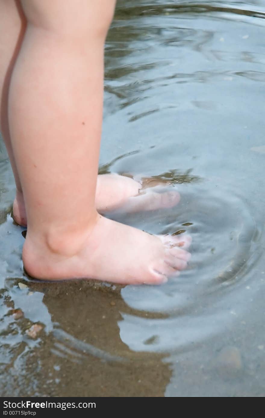 A child's toes getting wet in a lake