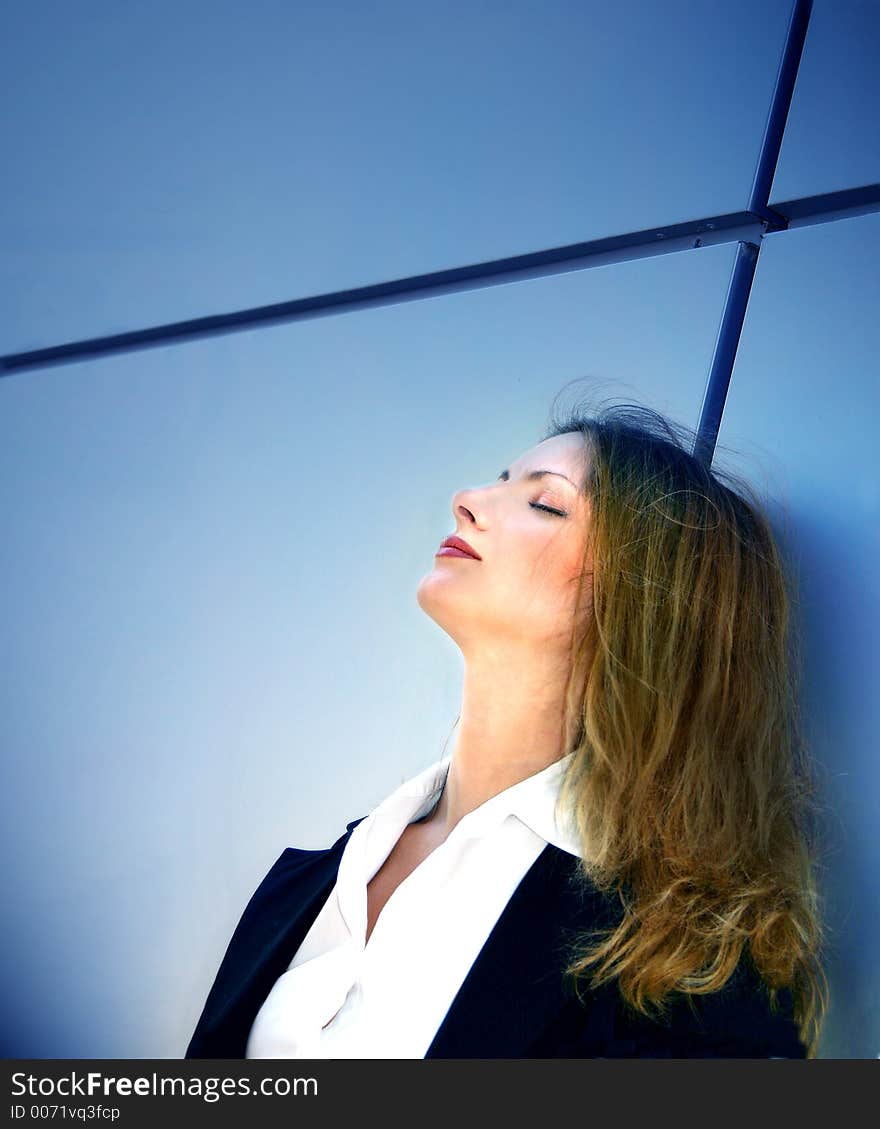 Business woman standing against a wall and thinking. Business woman standing against a wall and thinking