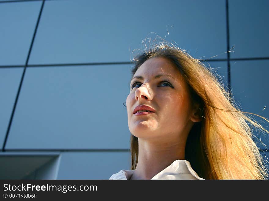 Confident young business woman basking in dusk light in front of her office building. Confident young business woman basking in dusk light in front of her office building