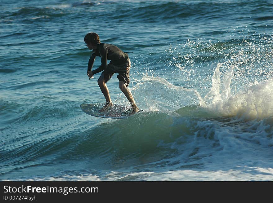 A boy on a skim board catching the wave. A boy on a skim board catching the wave