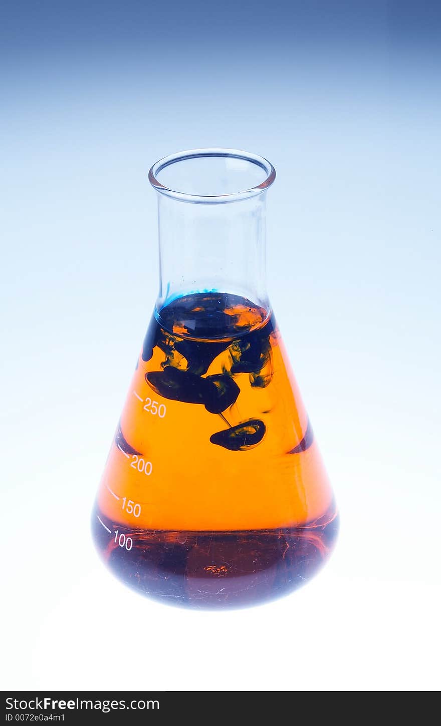 A laboratory glas filles with orange liquid and black clouds in it