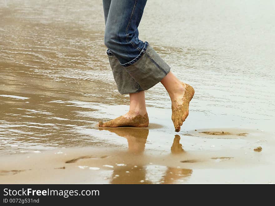 Legs of a girl is walking on the beach