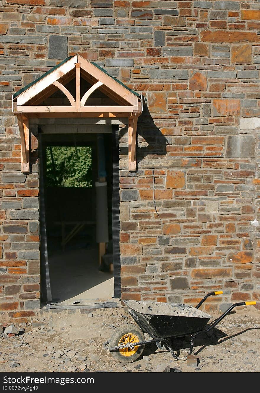 Doorway of a new house under construction with a wheelbarrow in the foreground. Doorway of a new house under construction with a wheelbarrow in the foreground.