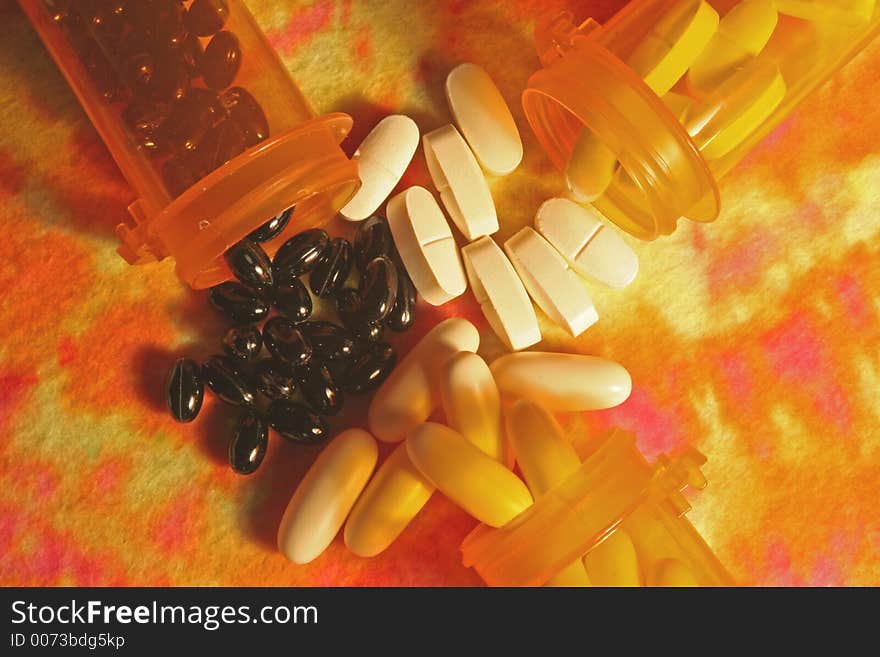 Horizontal image of three prescription bottles filled with pills spilling out on multi-colored background. Horizontal image of three prescription bottles filled with pills spilling out on multi-colored background