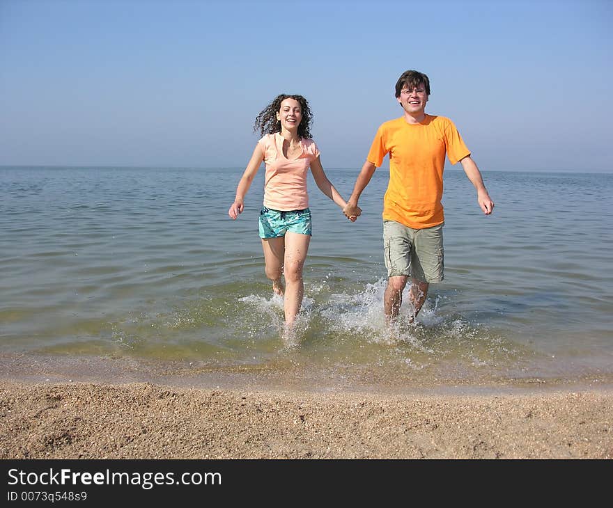 Couple run on beach from sea