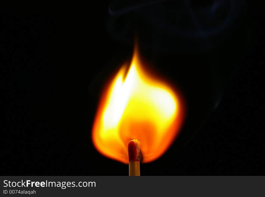 Closeup of a red-tipped wooden match stick at ignition. Red, orange, yellow, and white flame. Black background. Closeup of a red-tipped wooden match stick at ignition. Red, orange, yellow, and white flame. Black background.