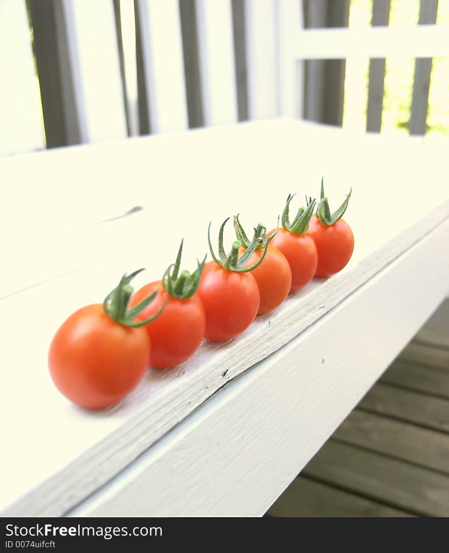 Red cherry tomatoes on an outdoor bench. Red cherry tomatoes on an outdoor bench