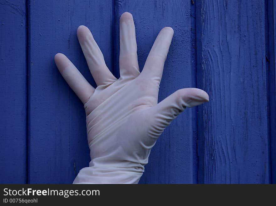 A hand in rubber glove on blue background