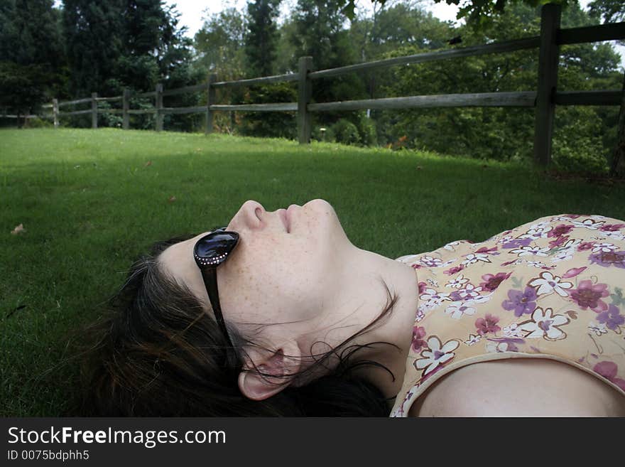 Woman in sunglasses lying down on green lawn. Woman in sunglasses lying down on green lawn