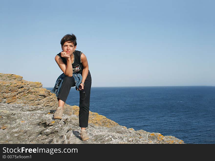 Woman on a cliff  looking at the sea. Woman on a cliff  looking at the sea