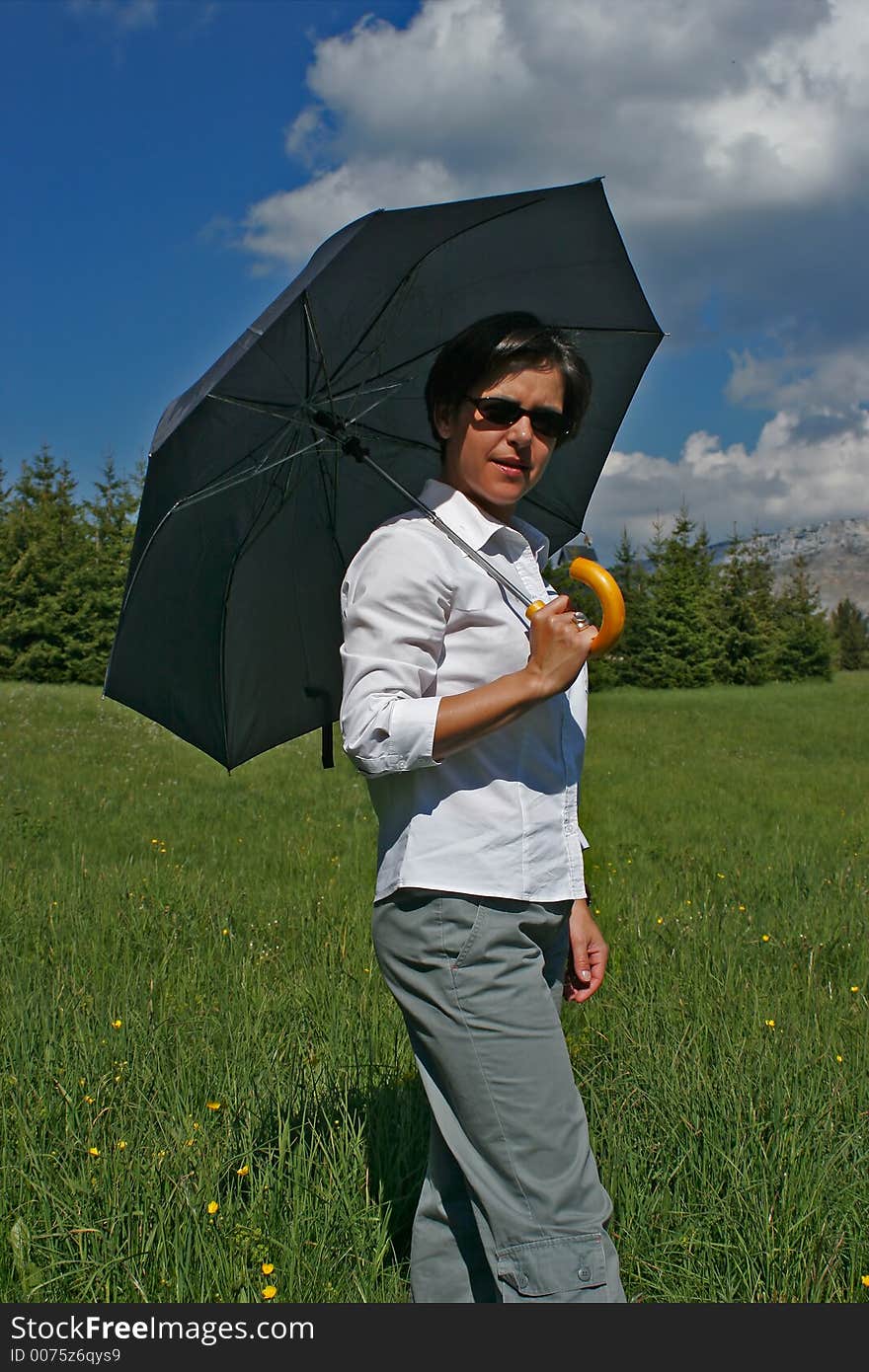 Woman going in a meadow with its umbrella. Woman going in a meadow with its umbrella