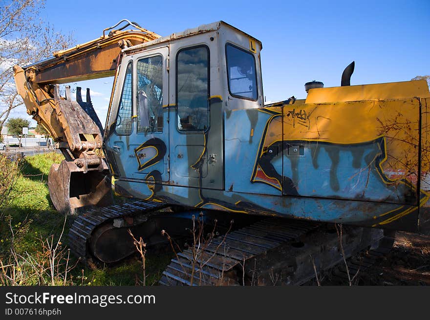 A graffitied excavator at a demolition site.