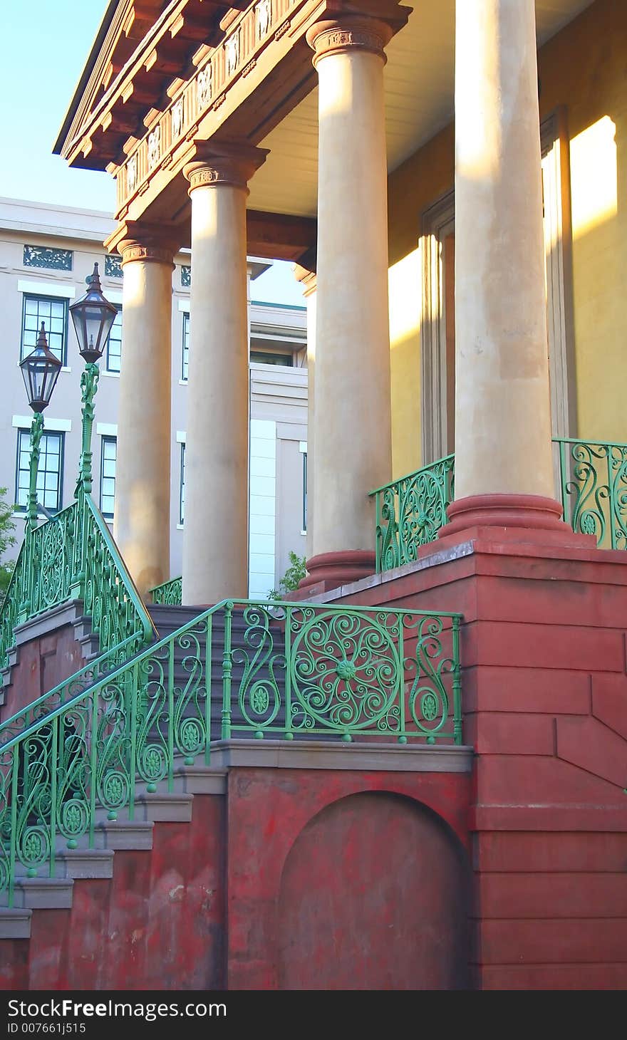 An elegant old building with 4 columns and a detailed stairway