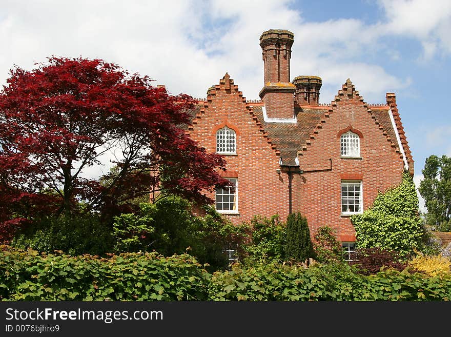 Old house with red leafed tree in the foreground