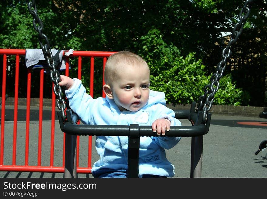 Happy child playing on swing in playground