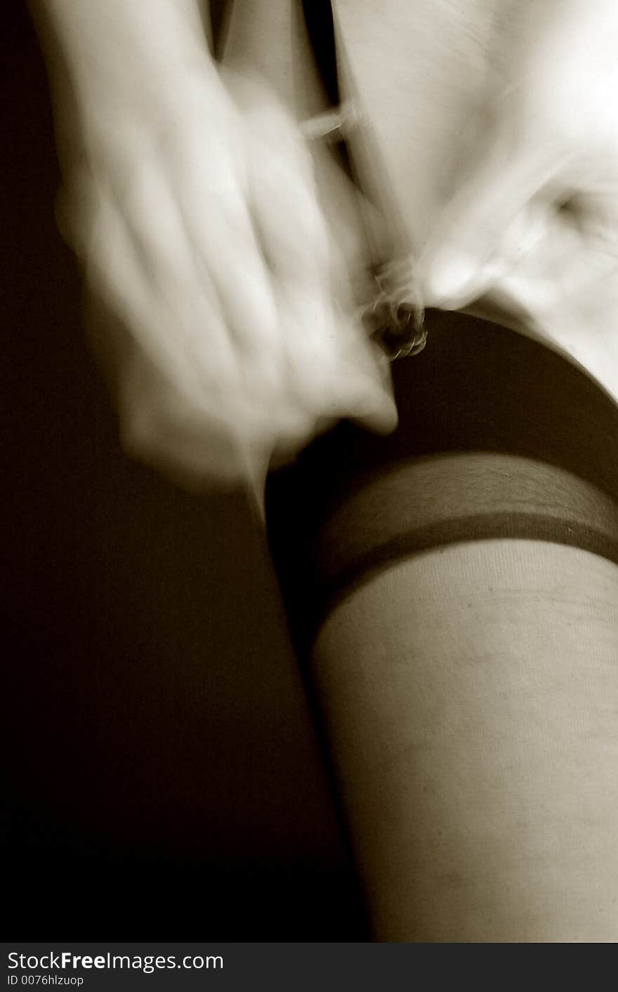 Woman putting on stocking, hand blurred. Woman putting on stocking, hand blurred.