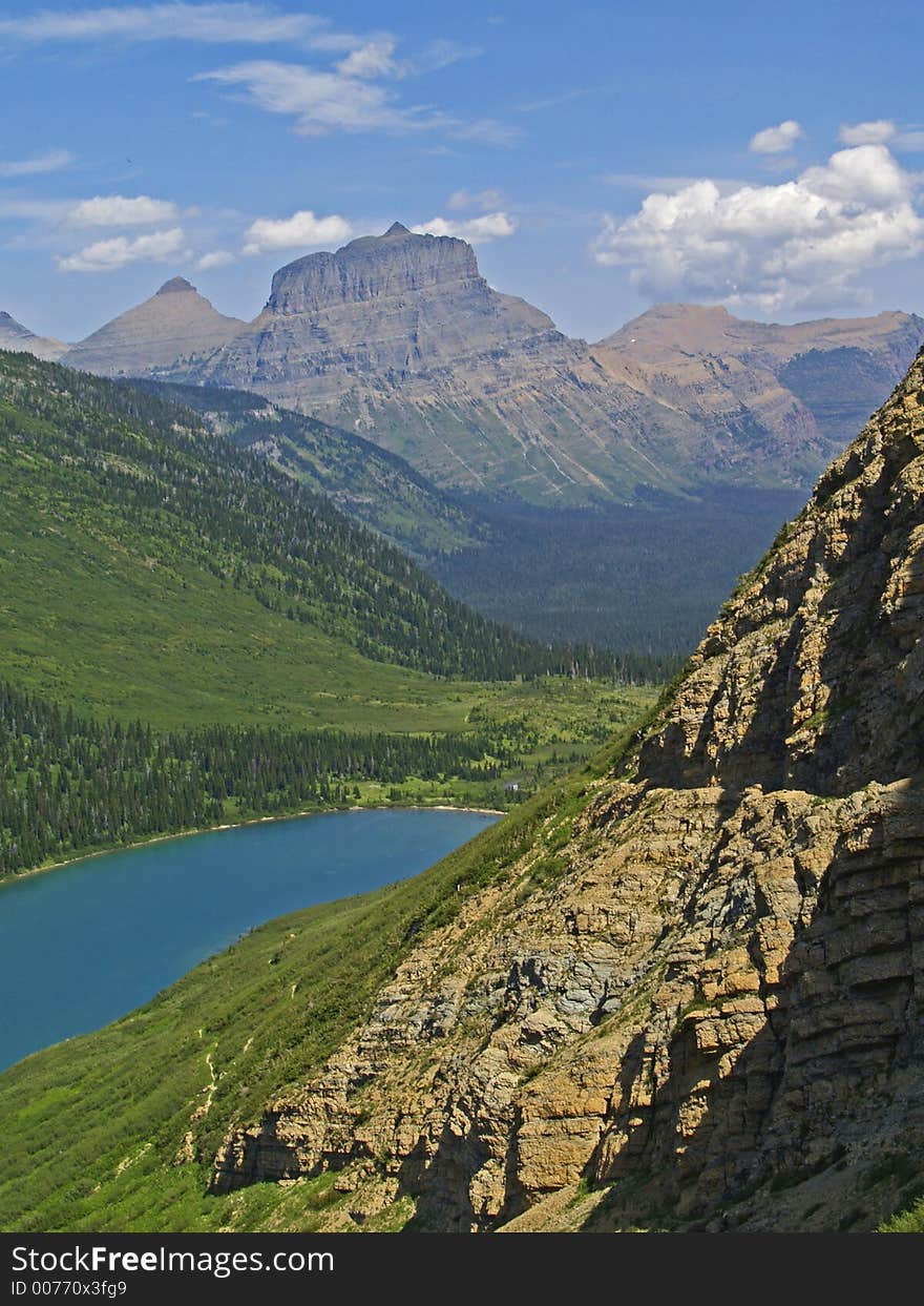 This image of the trail cut into the cliff above the lake with the mountains in the background was taken in Glacier National Park. This image of the trail cut into the cliff above the lake with the mountains in the background was taken in Glacier National Park.