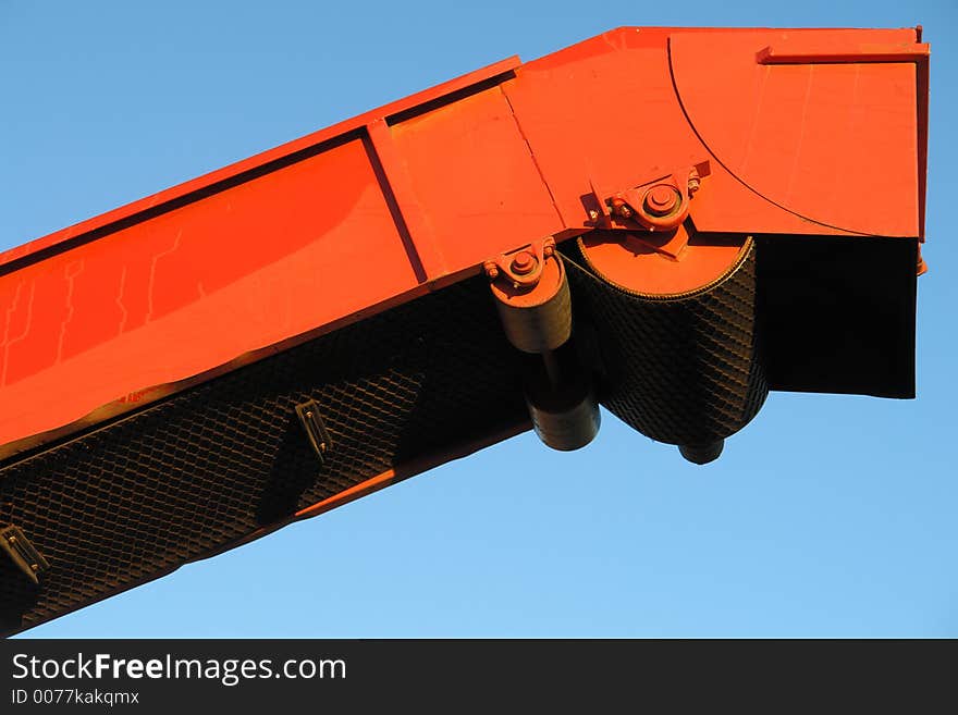 Red almond harvester against a blue sky.