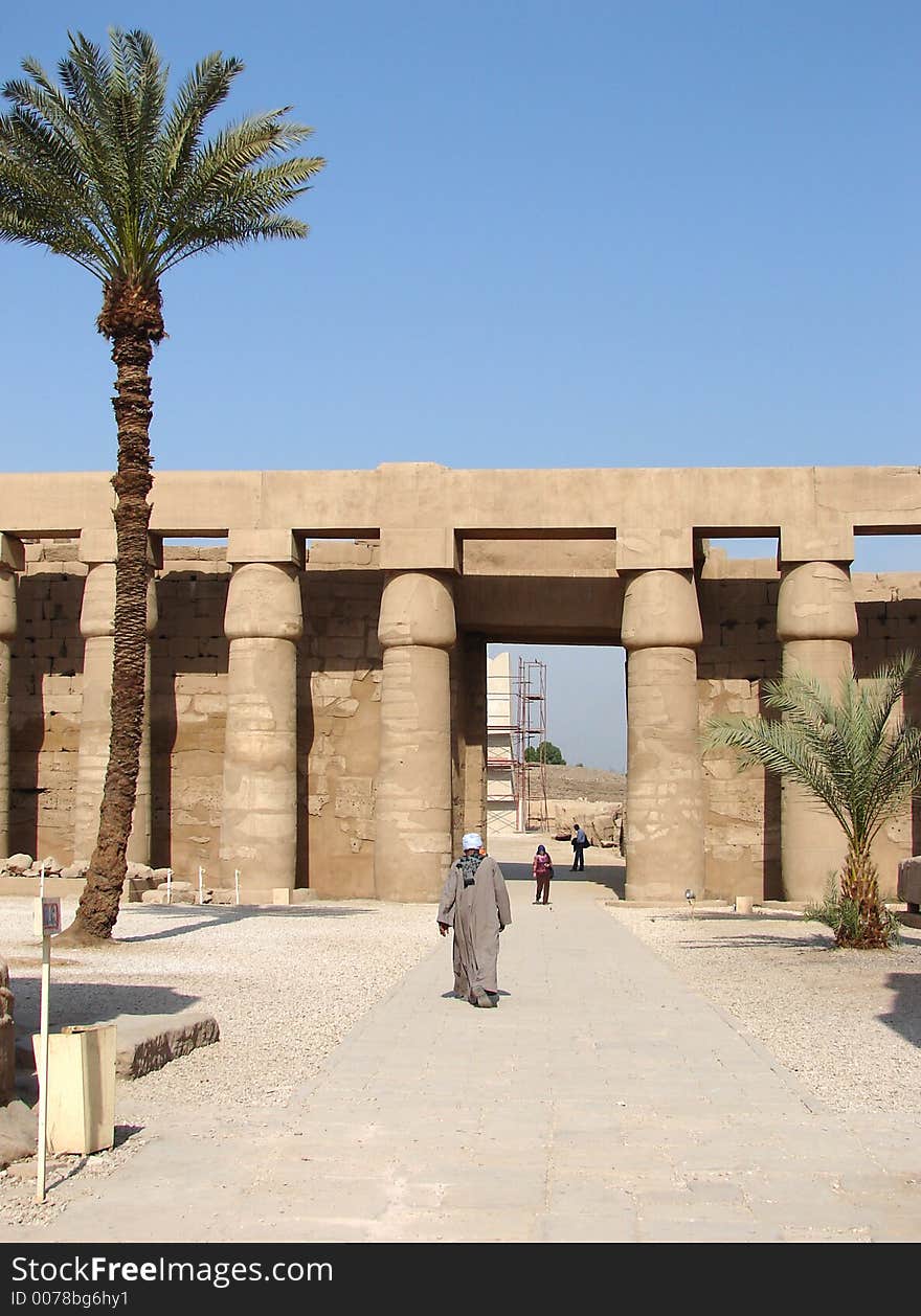 The touristic place Luxor with palm trees, pillars and a walking man