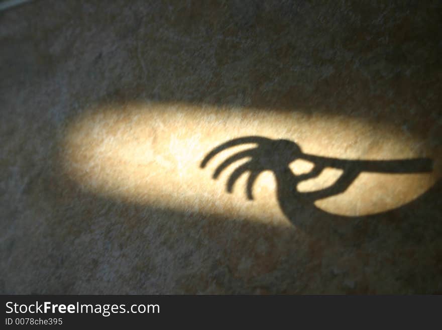 A shadow cast from a small metallic figurine (of someone playing a horn) makes for an interesting picture when placed in a beam of a late afternoon sunlight. A shadow cast from a small metallic figurine (of someone playing a horn) makes for an interesting picture when placed in a beam of a late afternoon sunlight.