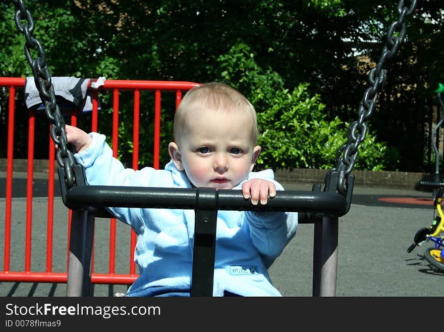 Happy child playing on swing in playground