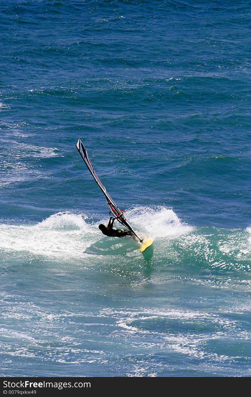 A windsurfer carves a wave while sailboarding in Hawaii. A windsurfer carves a wave while sailboarding in Hawaii