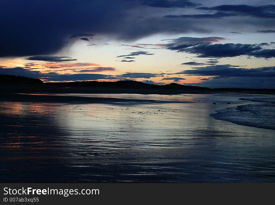 Sunset over a deserted beach with clouds coming in. Sunset over a deserted beach with clouds coming in