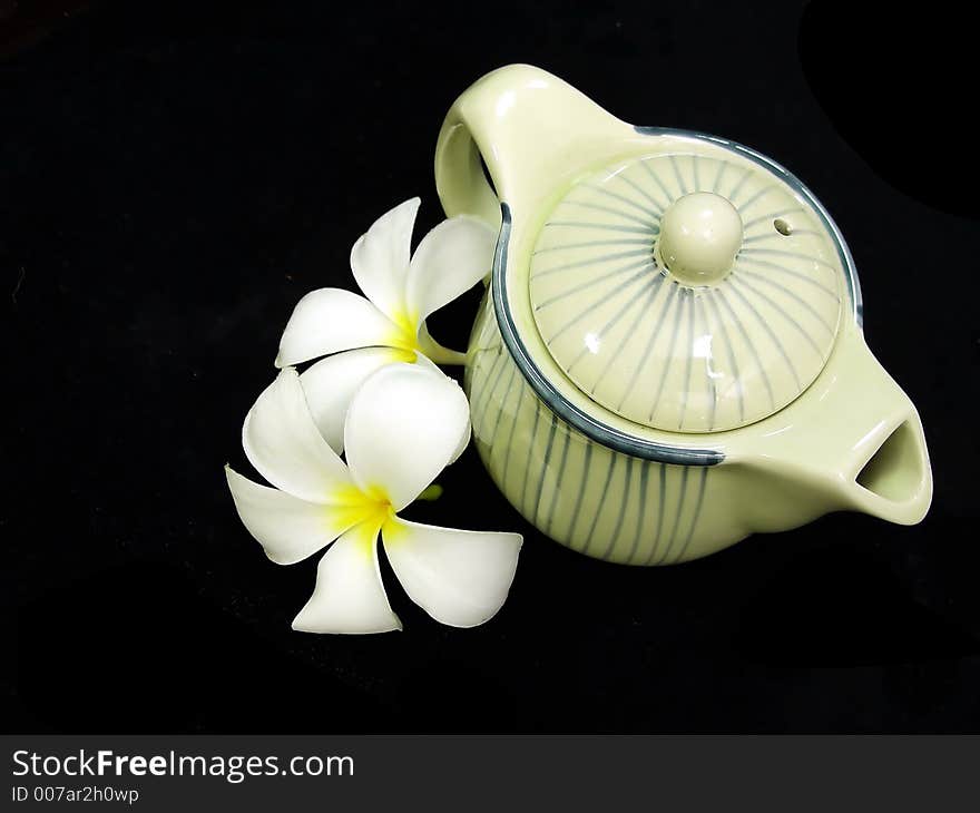 A photo of teapot and plumeria flower. A photo of teapot and plumeria flower