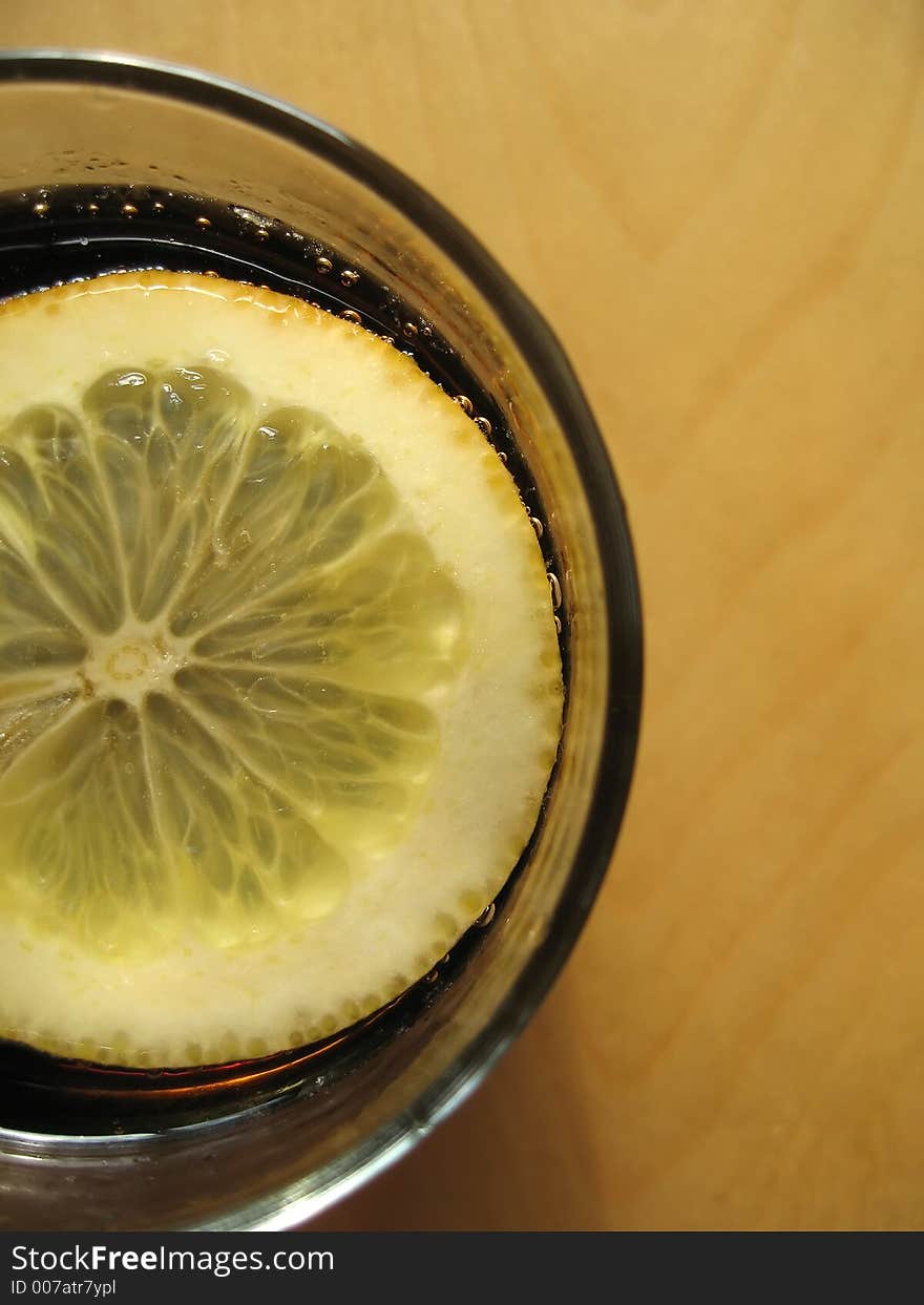 A slice of lemon in a cola cocktail drink. A slice of lemon in a cola cocktail drink.