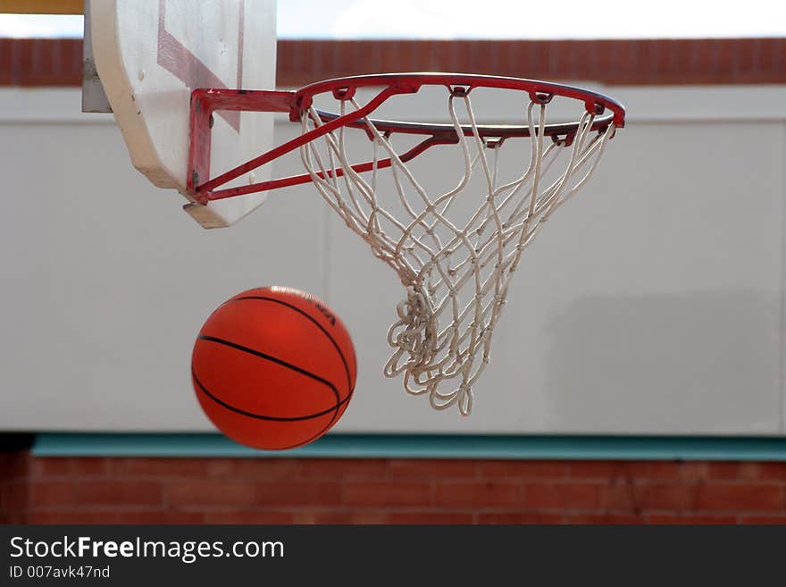 A basketball going through the hoop and net. A basketball going through the hoop and net.