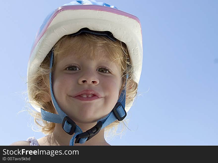 A cute little curly haired blond girl with her bicycle helmet on. A cute little curly haired blond girl with her bicycle helmet on.