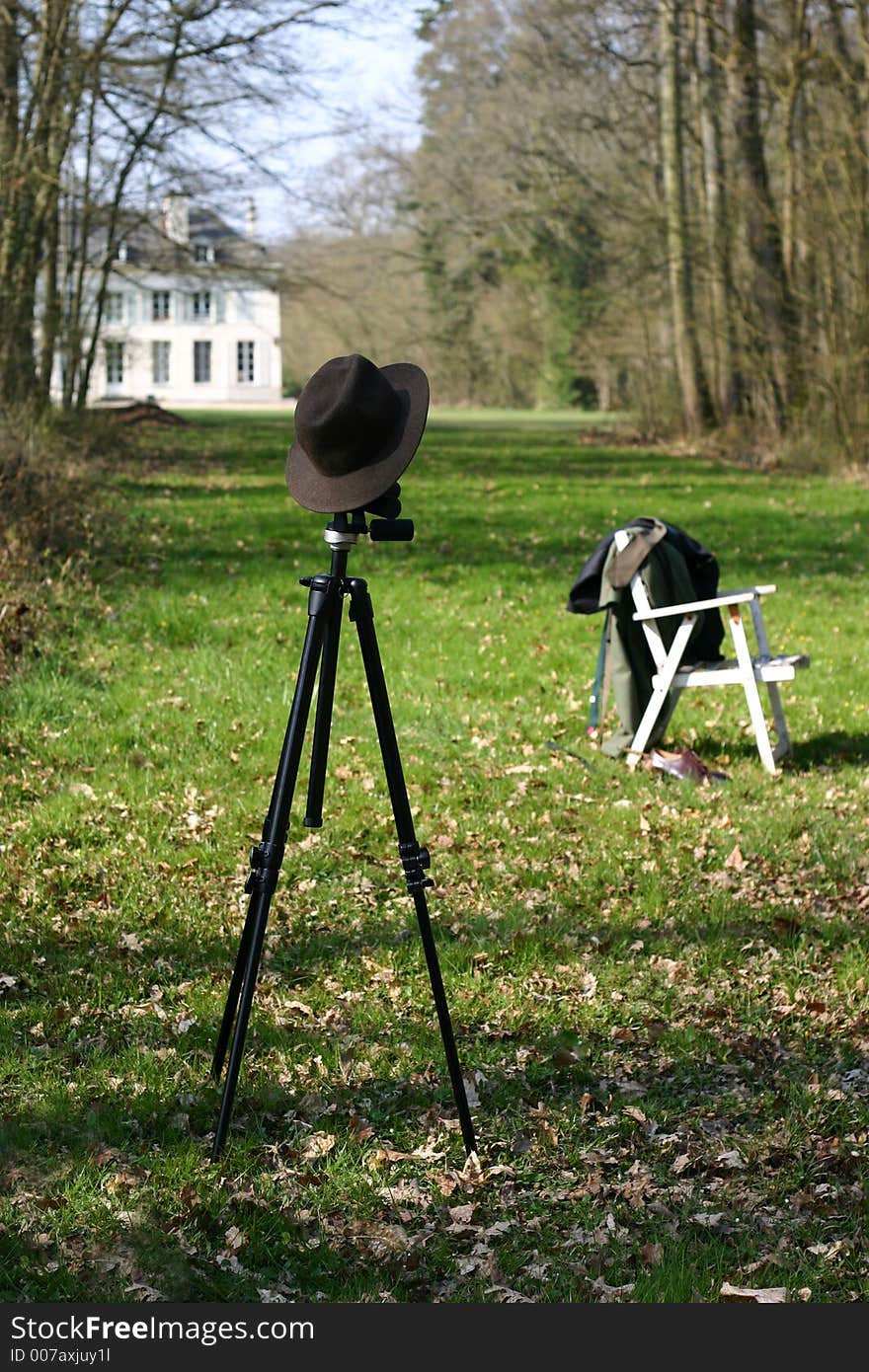 Felt hat on a tripod on green grass background.