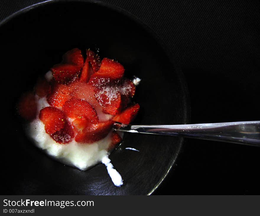 Strawberries with sugar and yoghurt in a plate on black background. Strawberries with sugar and yoghurt in a plate on black background.