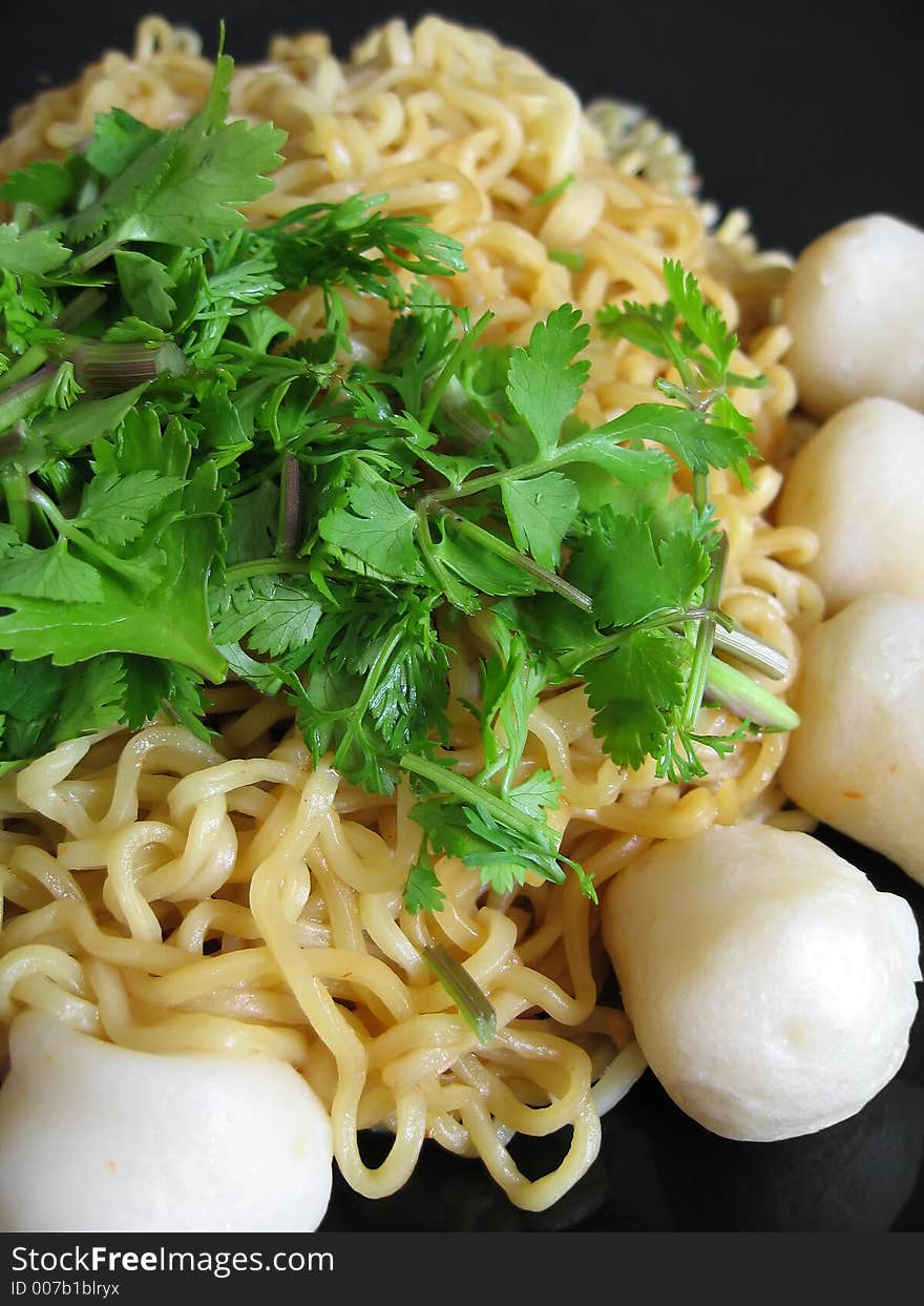 Seafood Asian stir-fry noodles with fish balls. Garnished with fresh coriander leaves.