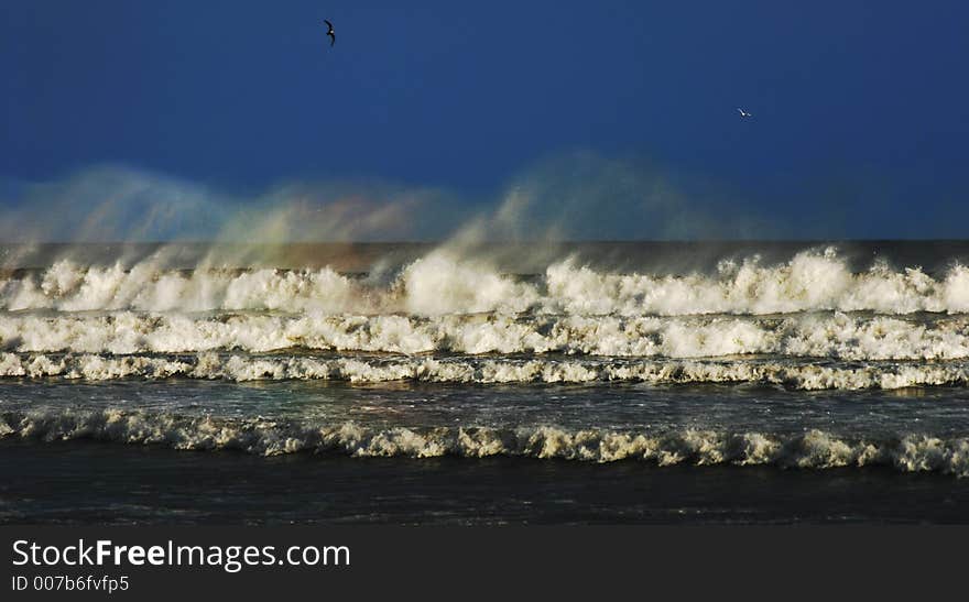 Waves breaking on the beach with rainbow colours in the spray. Waves breaking on the beach with rainbow colours in the spray