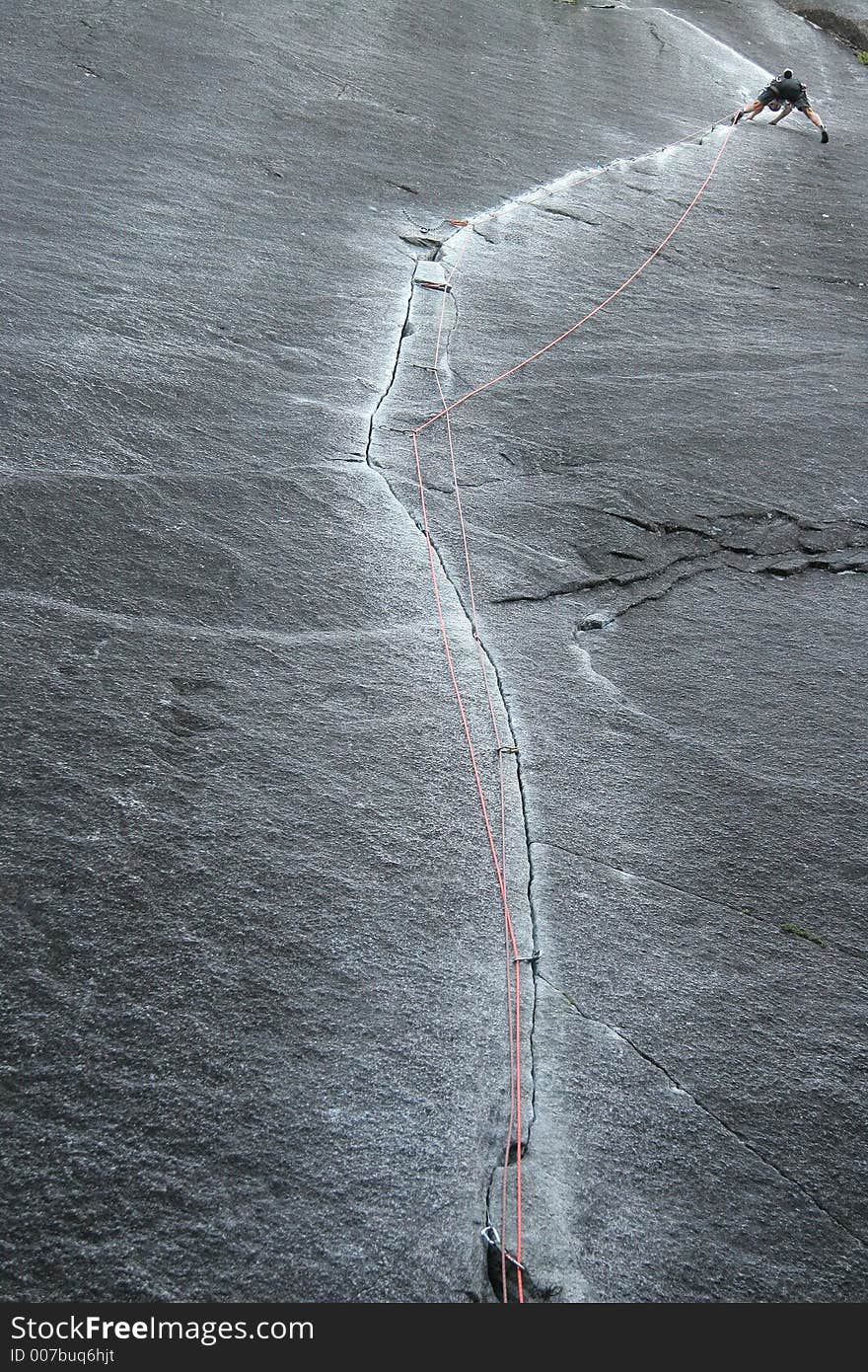 Rock climber climbs granite finger crack high onto a cliff. Rock climber climbs granite finger crack high onto a cliff.