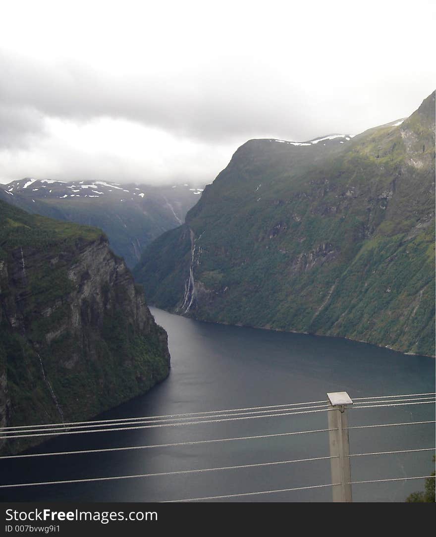 Stream flowing between two mountains in Norway...where the mountains seem to reach the clouds in the distance. Stream flowing between two mountains in Norway...where the mountains seem to reach the clouds in the distance