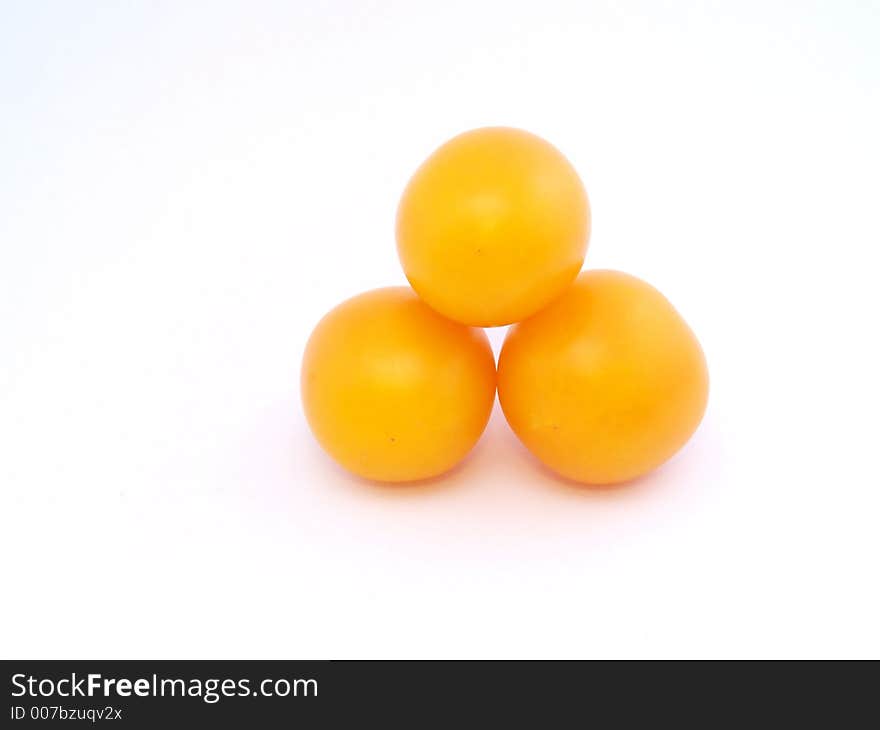 Three yellow tomatoes on the white. Three yellow tomatoes on the white