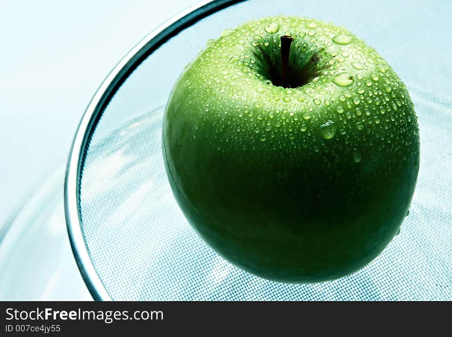 Wet green apple in brilliant drops of water