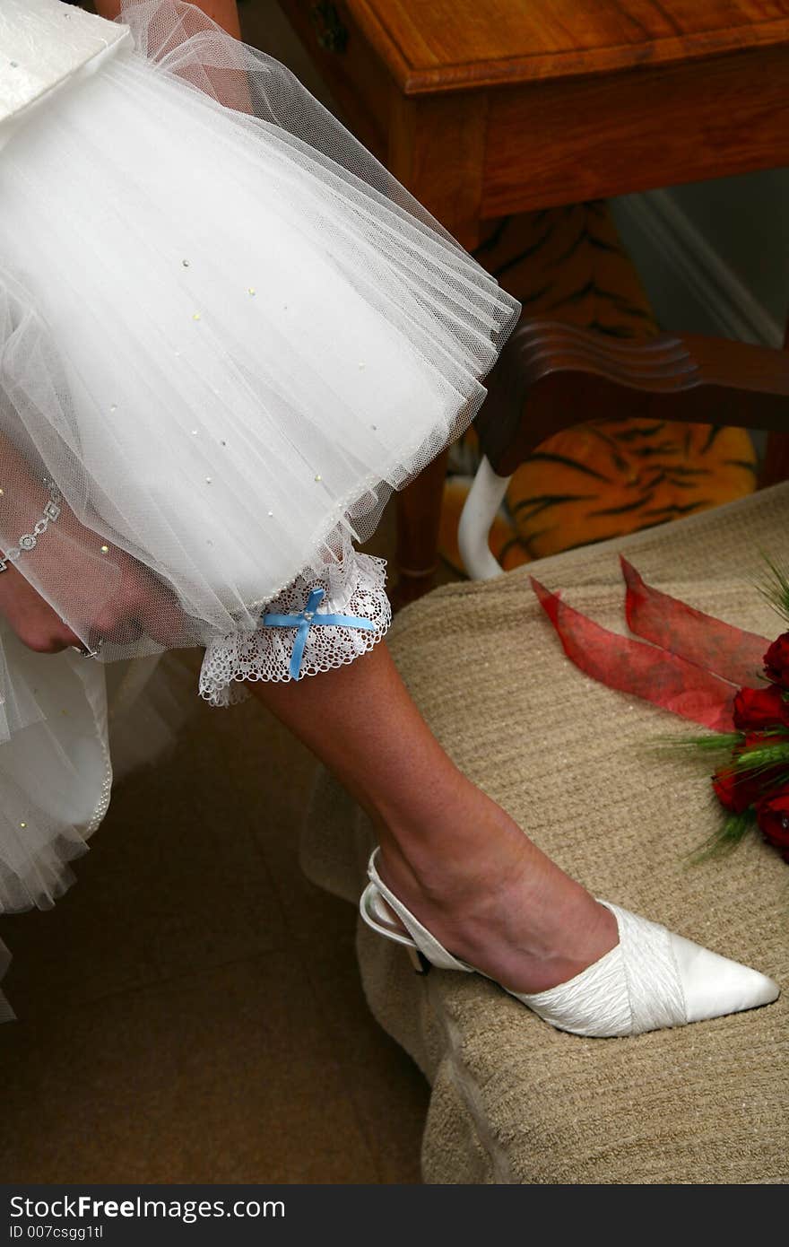 Bride putting garter on her leg. Bride putting garter on her leg