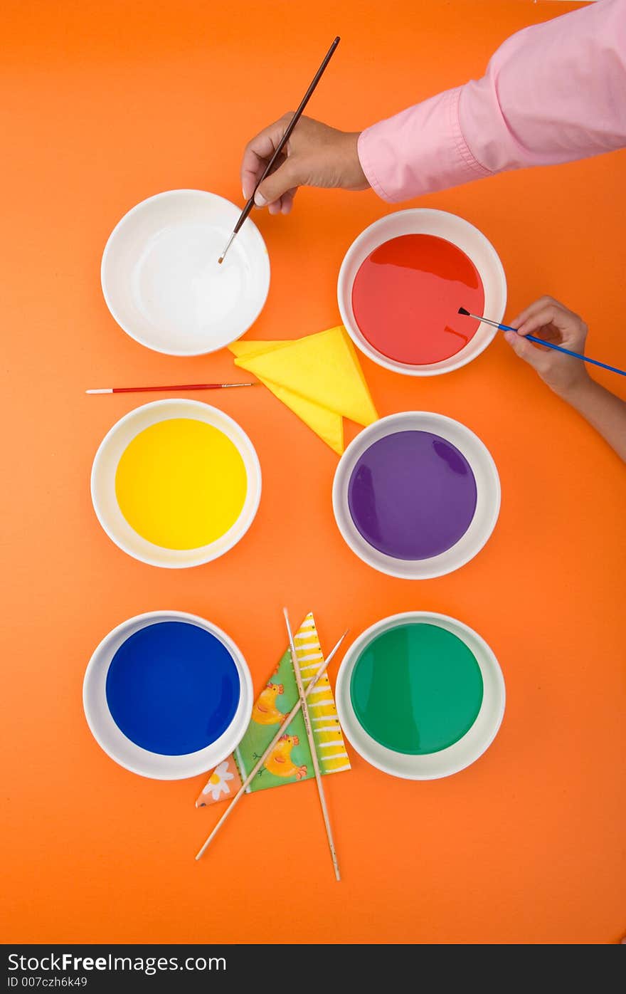 Overhead view of hands with paint and brushes. Overhead view of hands with paint and brushes