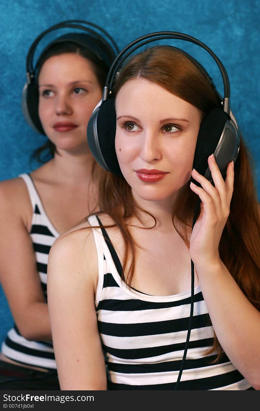 Two beautiful young woman wearing headphones and listen to music. Two beautiful young woman wearing headphones and listen to music.