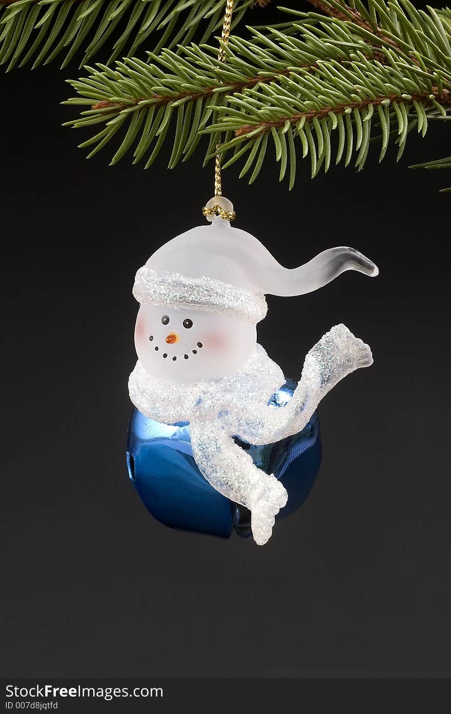 Blue snow bell Christmas tree ornament hanging on branch.